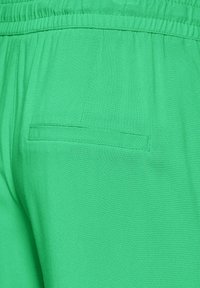 Zielone lekkie spodnie z materiału z elastycznym paskiem w talii, z pojedynczym tylnym kieszeniem i gładką teksturą.