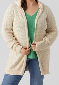 Cremfarbener Strickcardigan mit Kapuze, der ein strukturiertes Offene-Design und gerippte Bündchen aufweist. Über einem grünen, gerippten Oberteil mit tiefem V-Ausschnitt getragen.