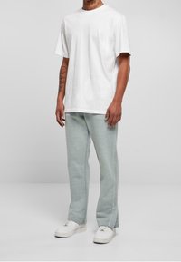 Vit bomull t-shirt med korta ärmar, i kombination med ljusgröna sweatpants som har en ren design och något avsmalnande ben.