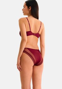 Ensemble de lingerie bordeaux comprenant un soutien-gorge avec des bretelles réglables et une culotte assortie avec des accents transparents et des finitions en dentelle le long des bords.