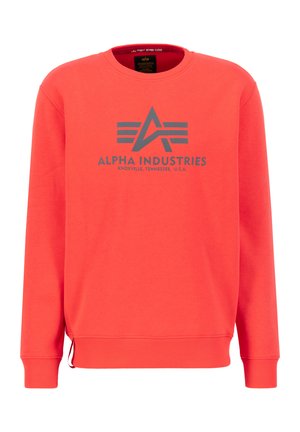 Rød sweatshirt med lange ærmer, rund hals og elastiske manchetter. Har et gråt logo "ALPHA INDUSTRIES" og "KNOXVILLE, TENNESSEE, U.S.A." foran.