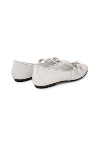 Ballerine bianche in pelle con punta affilata, caratterizzate da cinturini incrociati e dettagli hardware decorativi. Texture liscia e suola nera piatta.