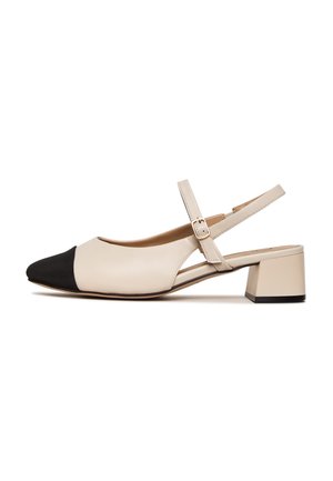 Beiger Slingback-Schuh mit niedrigem Absatz, schwarzer spitzer Schuhkappe und verstellbarem Schnallenriemen auf weißem Hintergrund.