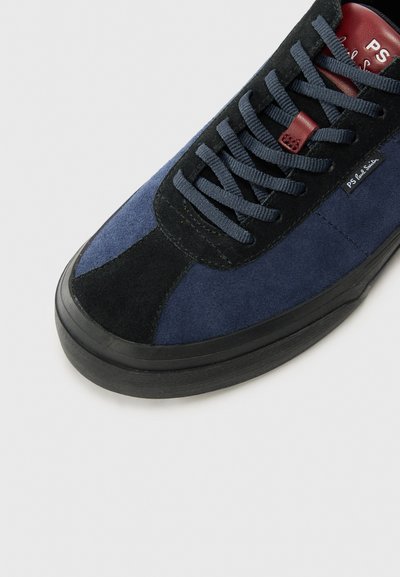 Sneaker din suede bleumarin cu accente negre, vârf rotund și talpă din cauciuc. Are șireturi asortate și un eticheta cu marcă pe limbă.