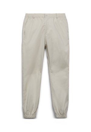 Pantaloni beige con vita elastica, chiusura con bottone, tasche laterali e polsini elastici alle caviglie, mostrati su uno sfondo bianco.