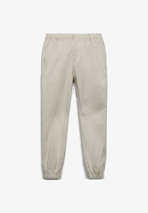 Pantaloni beige con vita elastica, chiusura con bottone, tasche laterali e polsini elastici alle caviglie, mostrati su uno sfondo bianco.