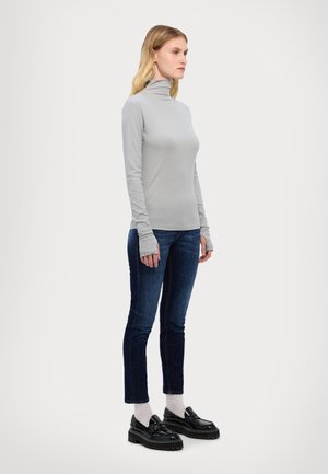 Grå langærmet turtleneck-top parret med mørkeblå jeans og sorte platform-lodden. Outfittet har en tætsiddende silhuet og blød tekstur.