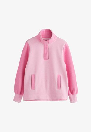 Světle růžový pulovr s vysokým límcem, dlouhými rukávy, předními kapsami a hladkou texturou s kontrastními akcenty na límci a kapsách.