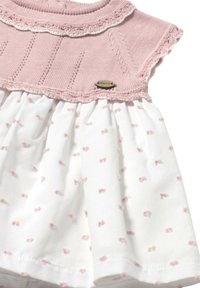 Vestido de punto rosa claro con cuello festoneado, que presenta una falda blanca con pequeños patrones de lazo rosa; incluye una pequeña etiqueta de hardware.