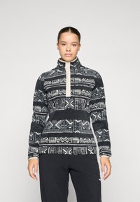 Fleece-pullover med høy krage, med et geometrisk svart og hvitt mønster. Front halv-zip-lukking og kontrasterende kremfarge.