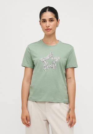 Light green cotton t-shirt featuring a large silver sequined star graphic at the center, short sleeves, and a crew neckline.