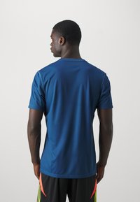 Short-sleeve, fitted blue athletic shirt made of smooth polyester, featuring a crew neck and minimal seam detailing.