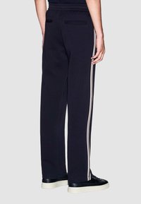 Marine joggers met een relaxte pasvorm, voorzien van twee verticale beige strepen aan de zijkanten en twee achterzakken. Zachte textuur en elastische tailleband.