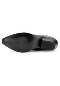 Suela de zapato de cuero negro que presenta una superficie lisa con punta afilada y un patrón de goma para agarre y tracción.