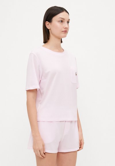 Light pink cotton t-shirt with short sleeves and a chest pocket, paired with matching shorts, featuring a relaxed fit and minimal design.