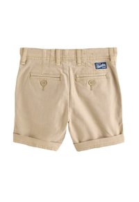 Shorts beige realizzati in tessuto leggero, con risvolti, due tasche posteriori con chiusura a bottone e una piccola etichetta del brand sulla cintura.