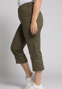 Pantalons courts vert olive avec une coupe ajustée, dotés de poches latérales et de coutures visibles. Le tissu a l'air lisse et léger.