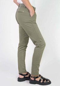 Olive green slim-fit pants made of cotton with a soft texture; features a back pocket and belt loops, paired with black strappy sandals.