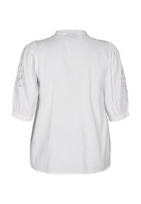 Vit blus med puffärmar, med intrikata spetsdetaljer på ärmarna. Slät textur och volangdesign vid halsen.