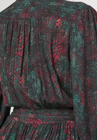Robe à manches longues avec un motif serpent noir, rouge et vert, dotée de détails froncés et d'une ceinture en tissu assortie à la taille.