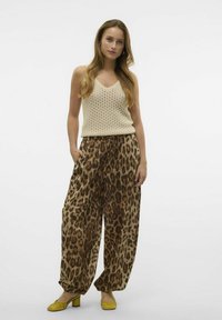 Beige strikket tank top, brede bukser med leopardprint i brune nuancer, og gule hælhæle. Enkel, løst siddende design.