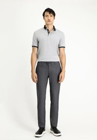 Grijze polo met zwarte kraagaccenten, in combinatie met grijze op maat gemaakte broeken en zwarte sneakers. Gladde stof, getailleerd ontwerp en minimalistische stijl.