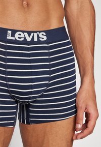 Marinblå och vita randiga boxerkalsonger med ett elastiskt midjeband med varumärke och en tajt passform, tillverkade av mjukt, stretchy material.