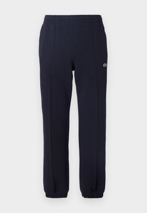 Pantaloni della tuta blu navy realizzati in tessuto morbido, con una vita elastica, polsini elasticizzati e un piccolo logo sul lato sinistro.