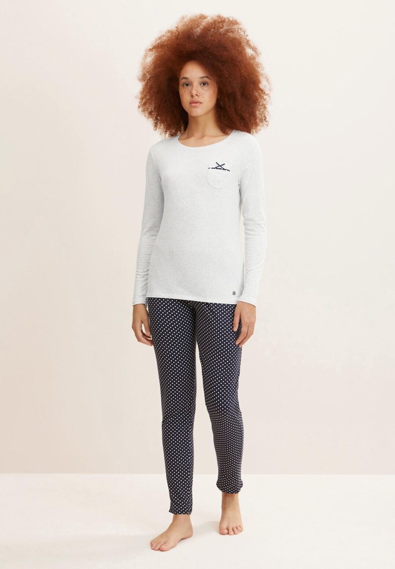 Light gray long-sleeve top with a navy pocket design, paired with navy polka dot leggings. Soft fabric, fitted shape, casual style.