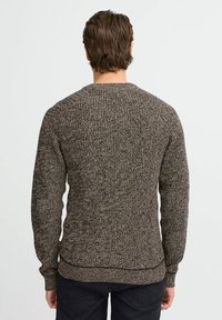 Knitted sweater in dark brown and beige hues, featuring long sleeves, crew neckline, and a textured pattern throughout the fabric.