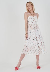 Weißes Midi-Kleid mit Spaghetti-Trägern, gestuftem Design und leichtem Stoff. Blumenmuster in Pink, Blau und Grün.