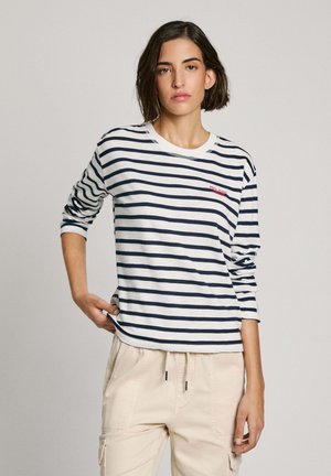 Camisa de manga larga a rayas en blanco y marino, con un cuello redondo y un pequeño logo rojo en el pecho. Material de algodón suave, ajuste relajado.