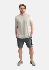 T-shirt di cotone grigio chiaro a maniche corte, abbinato a pantaloni cargo grigio scuro con tasche laterali e una vestibilità comoda.