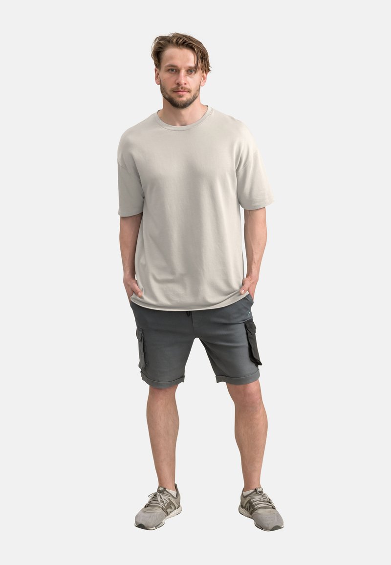 T-shirt di cotone grigio chiaro a maniche corte, abbinato a pantaloni cargo grigio scuro con tasche laterali e una vestibilità comoda.