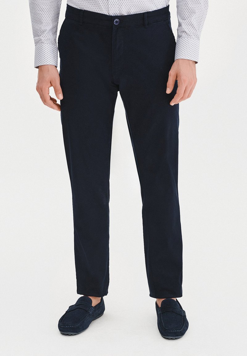 Granatowe bawełniane spodnie w dopasowanym kroju, z zamkiem błyskawicznym i zapięciem na guzik, kieszeniami z przodu oraz gładką fakturą.
