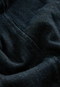 Donkerdenim stof met een subtiele textuur en een lichte glans. Zachte, gladde oppervlakte met zichtbare weefsels en draden, in een rijke zwarte kleur.