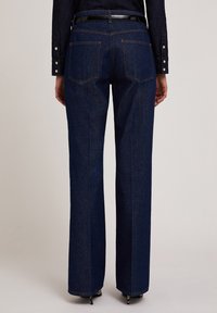Donkerblauwe denim jeans met een recht ontwerp, voorzien van een hoge taille, gestikte achterzakken en contrasterende oranje stiksels.