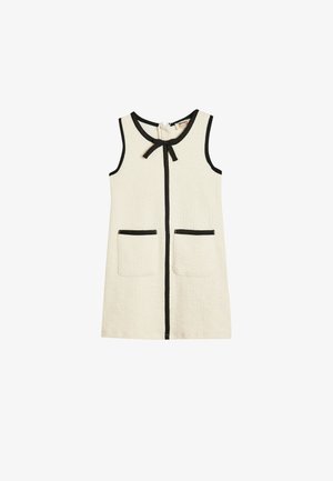 Vestido sin mangas en color crema con tejido texturizado, ribete negro a lo largo de los bordes, dos bolsillos frontales y un detalle de lazo en el escote.