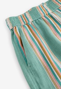 Leichtgewichtiger, türkis gestreifter Stoff mit vertikalen Linien in Rosa, Orange und Weiß. Der elastische Bund und die seitlichen Taschen erhöhen die Funktionalität.