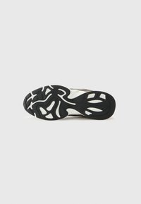 Black rubber shoe sole with white accents. Features a wavy tread pattern and raised sections for grip and stability. Lightweight design.