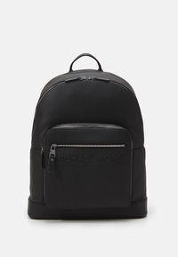 Μαύρο σακίδιο από δέρμα με λείο φινίρισμα, επενδυμένη μπροστινή τσέπη με φερμουάρ και λαβή στην κορυφή. Διαθέτει ανάγλυφο λογότυπο μ προστά.