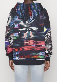 Sudadera con capucha de tela oscura con patrones digitales vibrantes en rojo, verde, azul y blanco. Corte holgado con puños y dobladillo acanalados.