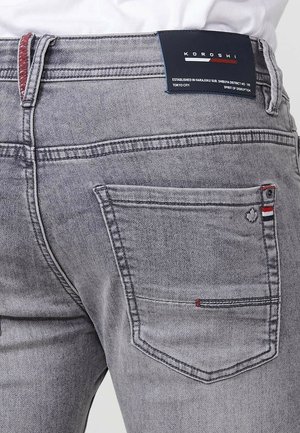 Graue Jeans aus Denim mit slim Fit, featuring einem roten Akzent an der Gesäßtasche, einem Logolabel und kontrastierendem Nähen.