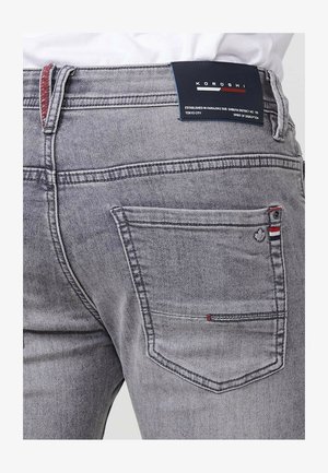 Hallid denim-jeansid, millel on kitsas lõige, punane aktsent tagataskul, logotag ja kontrastne õmblus.