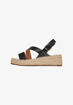 Czarne skórzane sandały na klinie z grubą plecioną podeszwą z juty, z paskiem krzyżującym się na stopie, regulowanym paskiem na kostkę oraz teksturowaną podeszwą zapewniającą przyczepność.