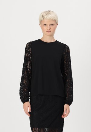 Black blouse with solid body and long lace sleeves. The lace features a floral pattern. The design is loose-fitting, with a round neckline.