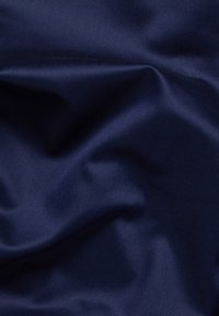 Ciemnobłękitny materiał satynowy o gładkiej, błyszczącej fakturze. Posiada subtelne fałdy i zagniecenia, które ukazują jego giętką strukturę i połysk.