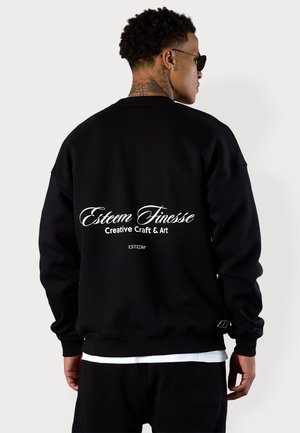 Schwarzer Pullover aus Baumwolle mit Rundhalsausschnitt, lockerer Passform und weißem Textlogo auf der Rückseite mit der Aufschrift: "Esteem Finesse Creative Craft & Art."