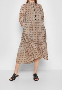 Beige midi mekko mustalla kuviolla, frillikaulus, puffihihat ja kerroksellinen hame. Yhdistetty mustiin remmikenkiin.