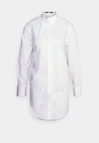 Chemise blanche à manches longues avec col mao, en coton, dotée d'une coupe droite et d'une fermeture à boutons sur le devant. Texture lisse.